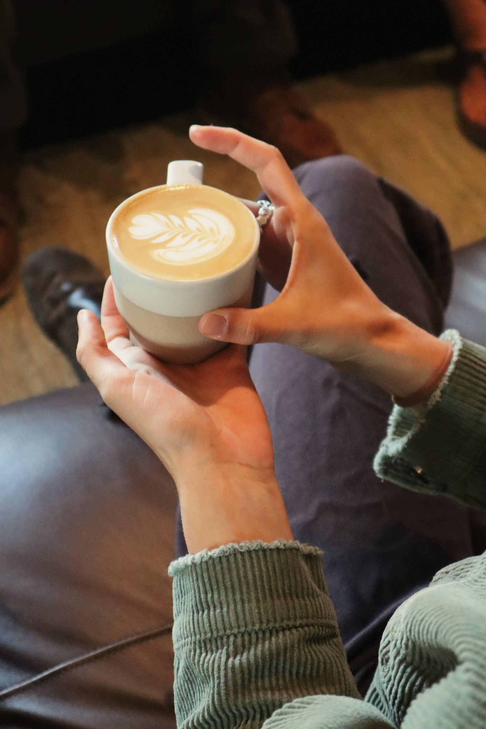 Hands holding a latte with leaf art