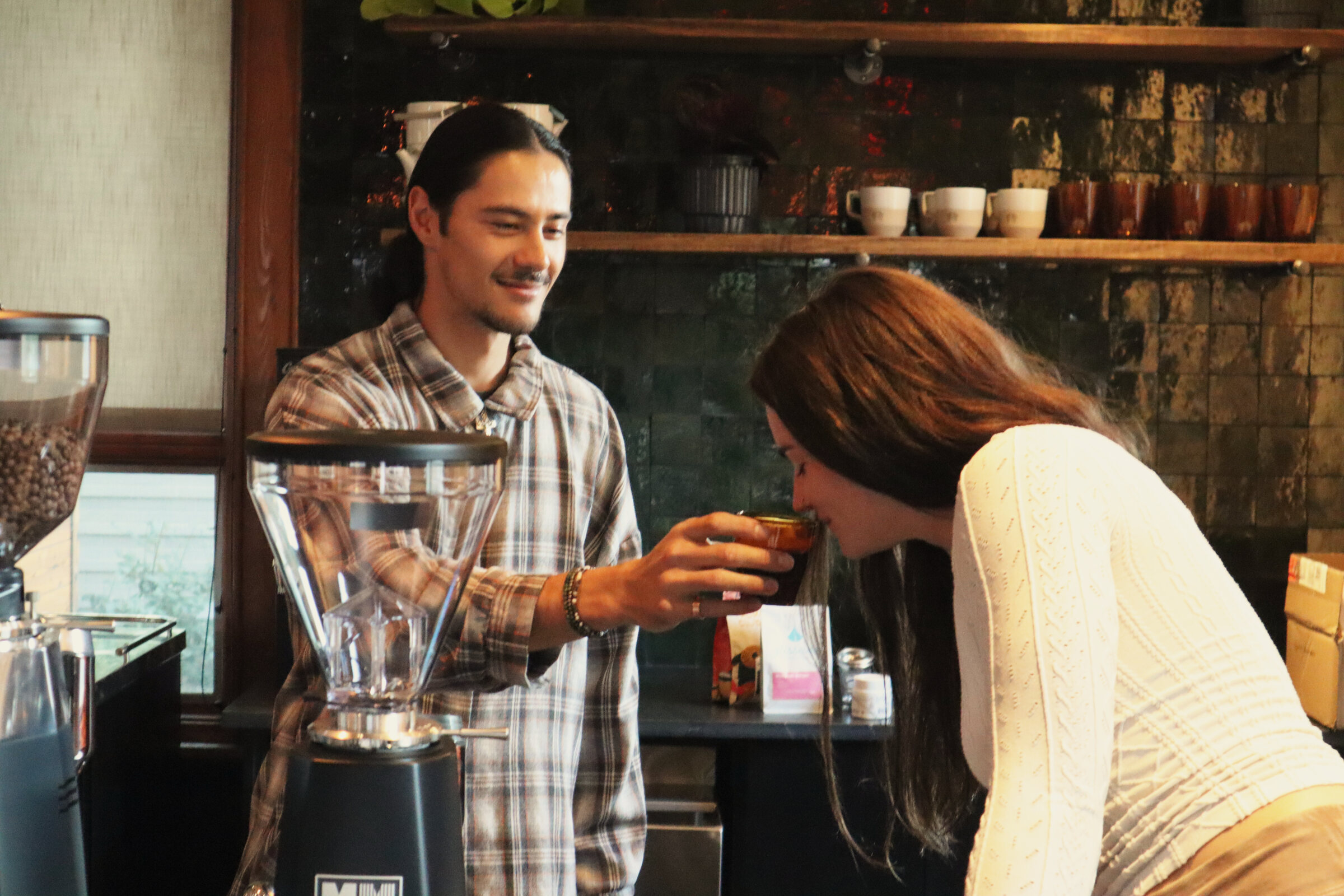 A barista pouring coffee while a guest looks on