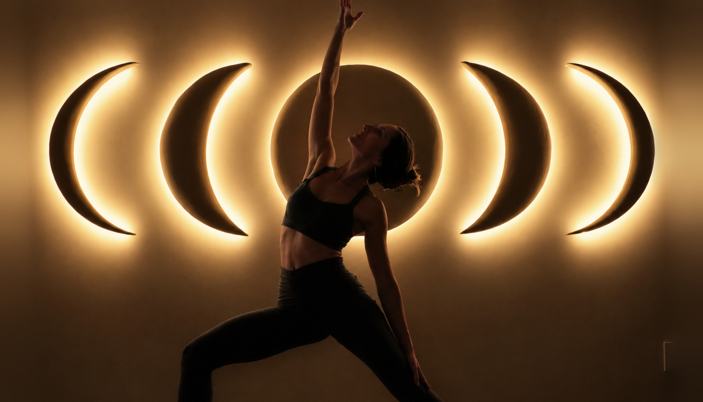 A silhouetted woman in reverse warrior under glowing moon lights