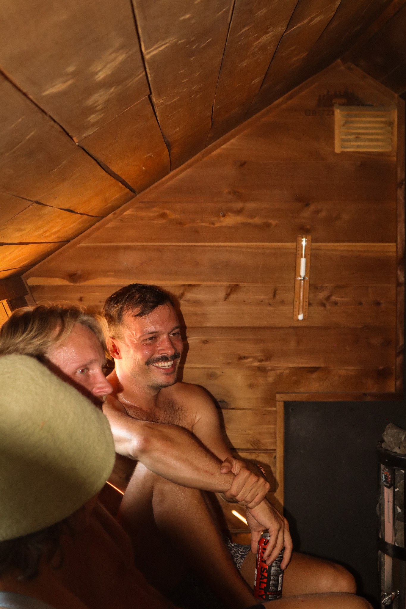 Two friends laughing on the sauna bench